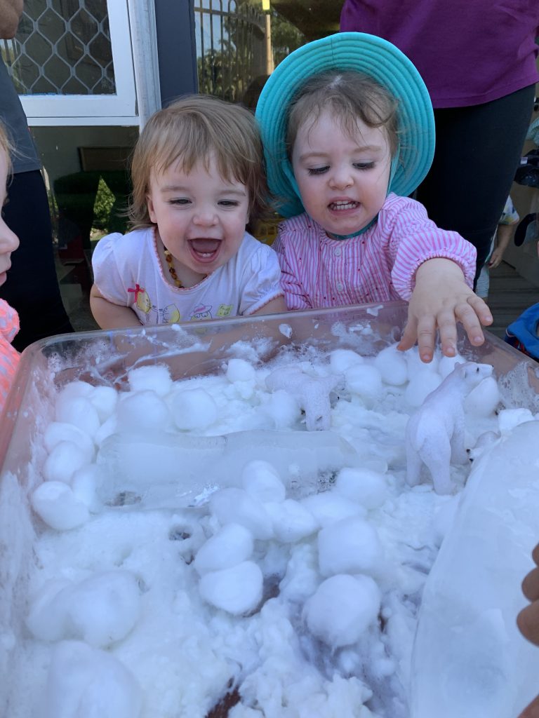 Toddler children excited by polar bear sensory play